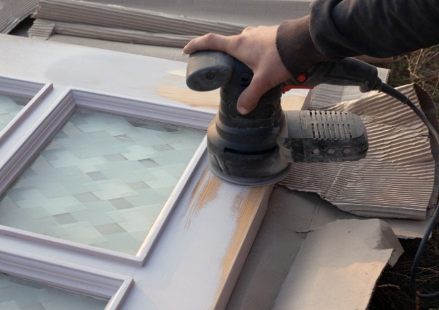 Carpintero lijando y preparando puerta en taller